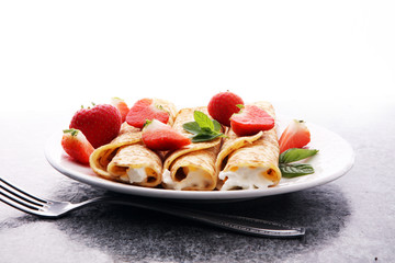 Crepes with jam, berries and sugar powder. Homemade pancakes, delicious breakfast.