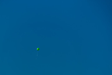 green balloon flies in a blue sky