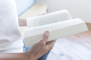 Fototapeta na wymiar Closeup of a reader reading a book at home