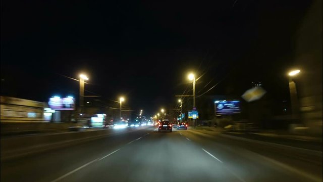 Time lapse of driving a car in the city at night time. POV. Hyper laps in the evening downtown.