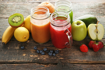 Sweet smoothie in glass jars with fruits on grey wooden table
