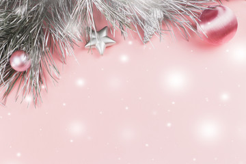 Christmas border with fir branches, christmas balls and silver ornaments on pastel pink background