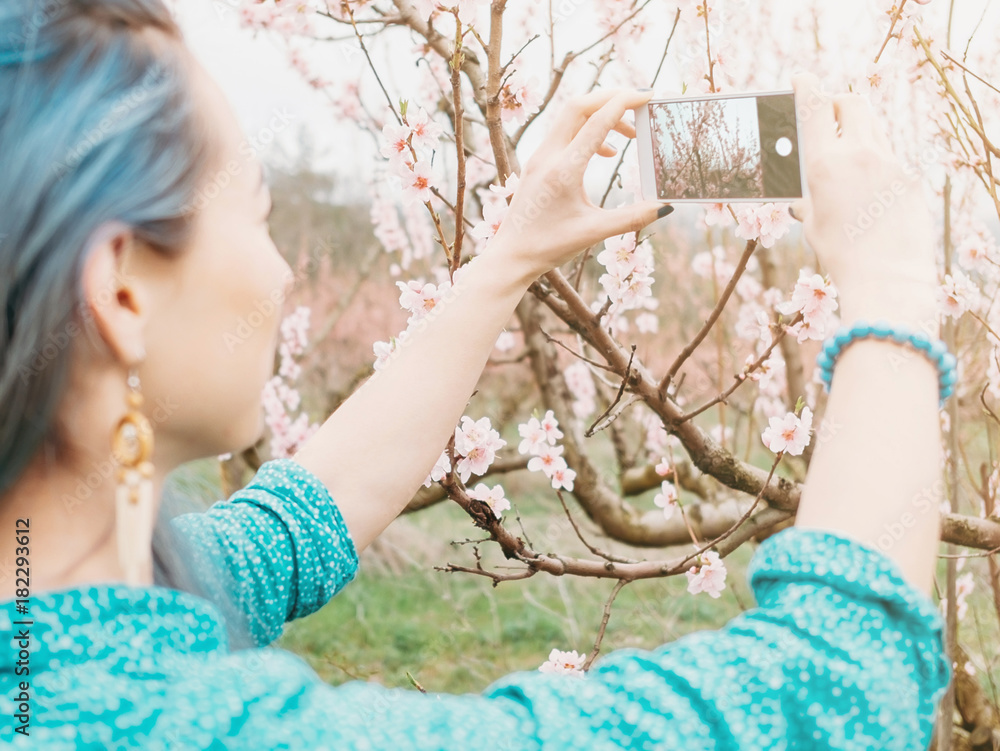 Wall mural woman taking photo blossoming tree.