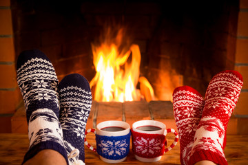 Couple in Christmas socks near fireplace - Powered by Adobe