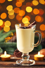 Eggnog in glass with cinamon and star anise on lights background