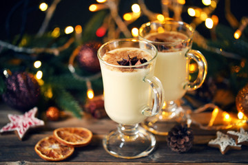 Eggnog in glasses with cinamon and star anise on wooden table