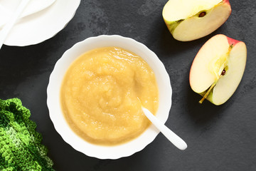 Fresh homemade apple sauce in bowl, photographed overhead on slate with natural light (Selective...