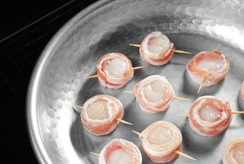 Frying pan with bacon wrapped scallops on table