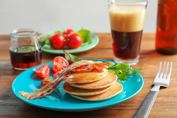 Plate with tasty pancakes and bacon on table