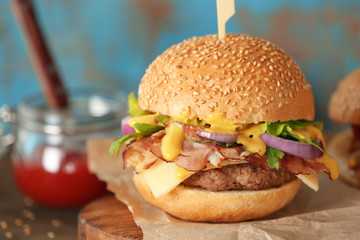 Tasty burger with bacon on wooden board