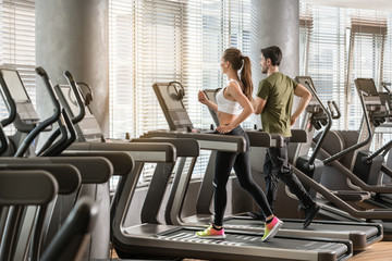Frau und Mann laufen im Fitnessstudio auf dem Laufband