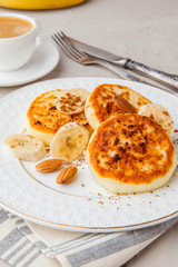 Cottage cheese pancakes with banana, syrniki on white rustic plate