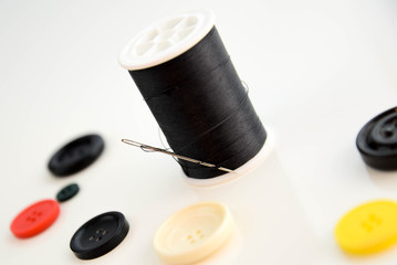 threaded needle, black thread spool and buttons