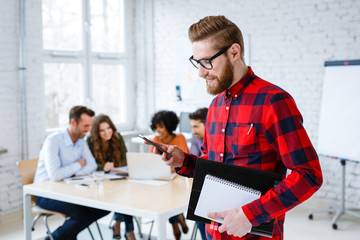 Young adult student browsing his phone at university classrom