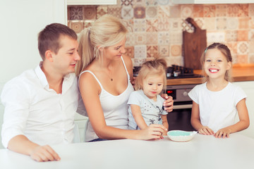 Smiling young parents and their little children daughter are very happy at kitchen home