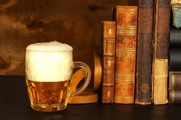 Poster Im Rahmen Glass of cold beer and old books. Rest with the book. © martinfredy