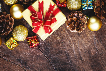Christmas or New Year background with pine cones,gift box on red ribbon,golden ball of Xmas decorations and fir branches, flat lay, blank space for a greeting text on wooden
