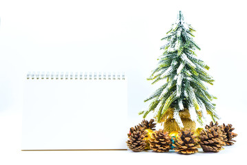 Christmas or New Year background with blank note pad,pine cones,gift box,golden ball and pine tree of Xmas decorations and fir branches, flat lay, blank space for a greeting text on white