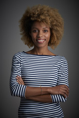Studio portrait of a beautiful happy afro-american ethnicity woman standing against at isolated gray background while looking at camera and smiling.