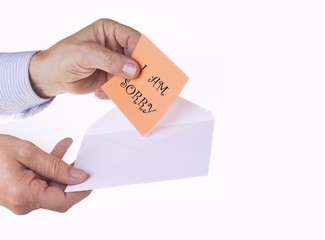 White envelope with paper note with man hand on the white background. I am sorry concept.