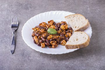 Chicken meat with beans sauce with bread on the plate on white.