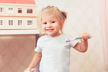 Little happy baby girl with toothbrush smiling and looking at camera