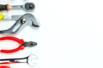 Top view of Working tools,wrench,socket wrench,hammer,screwdriver,plier,electric drill,tape measure,machinist square and safety glasses on white background.flat lay design