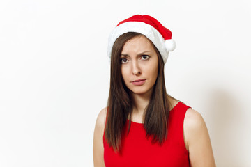 Beautiful caucasian young displeased and discouraged woman wearing red dress and Christmas hat on white background. Santa girl isolated portrait. New Year holiday 2018 concept