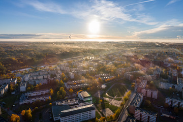 Fototapeta premium Aerial view of beautiful sunrise over the city. City in fog, misty landscape.
