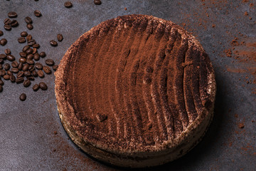 Italian frozen cake - tiramisu dessert on a dark background with coffee beans and powdered cocoa powder