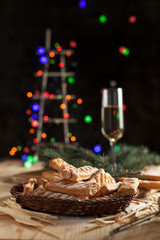 glasses with champagne, biscuits, a Christmas tree and New Year's lights on a New Year's festive table