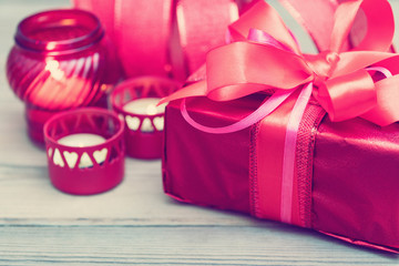 Red gift box with ribbon, surrounded by candles.