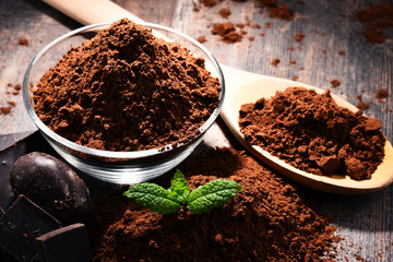 Composition with bowl of cocoa powder on wooden table
