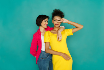 Two smiling girlfriends having fun at azur studio background