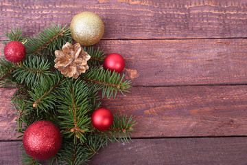 Fototapeta na wymiar Christmas or New Year background: fur-tree, branches, colored glass balls , decoration and cones on a wooden background