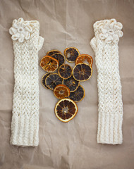 White mittens, dried orange slices and pink heart on paper background.