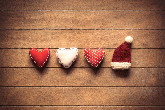 Heart shapes and Santa Claus hat on wooden background.