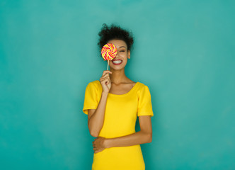 Happy girl with lollipop at studio background