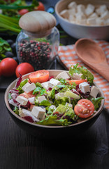 Greek salad and vegetables on the black wood table 