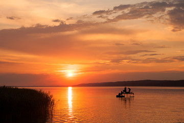Fototapeta na wymiar Beautiful sunset over Lake Balaton with silhouettes of anglers an reed