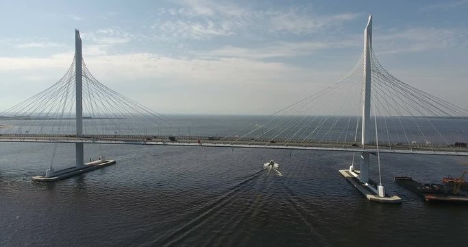 Motorboat passing under suspension bridge in Petrovsky fairway. WHSD viaduct above sea. St. Petersburg, Russia