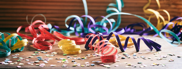 Colorful confetti and serpentines on wooden background
