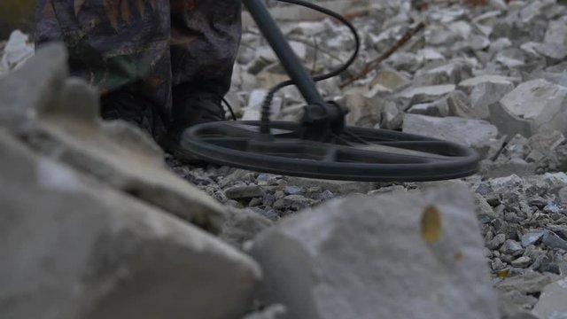 The soldier works with a mine detector in the ruins of houses in search of mines and explosives