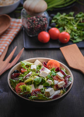 Greek salad and vegetables on the black wood table 