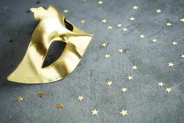 Golden mask with stars on concrete background