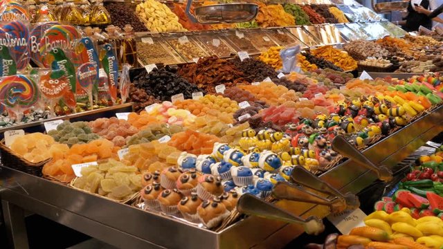 Large Counter with Colorful Sweets with Various Assorted Chocolate Candy in La Boqueria Market. Barcelona, Spain. Large counter with various Candy in glaze at Mercat de Sant Josep.