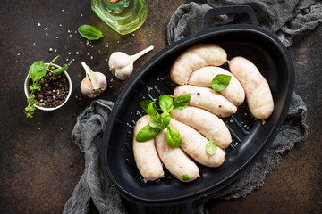 Raw homemade sausages on slate background, with basil and spices.
