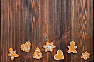 Christmas gingerbread cookies of different shapes on a brown wooden table. Copy space.