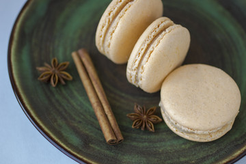 Sweet macarons and anise star on a green ceramic plate.  Close-up.