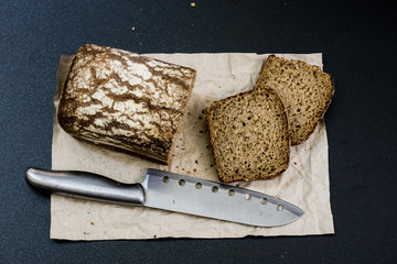 Black bread on gray paper. Spices and oil next to slices of bread.